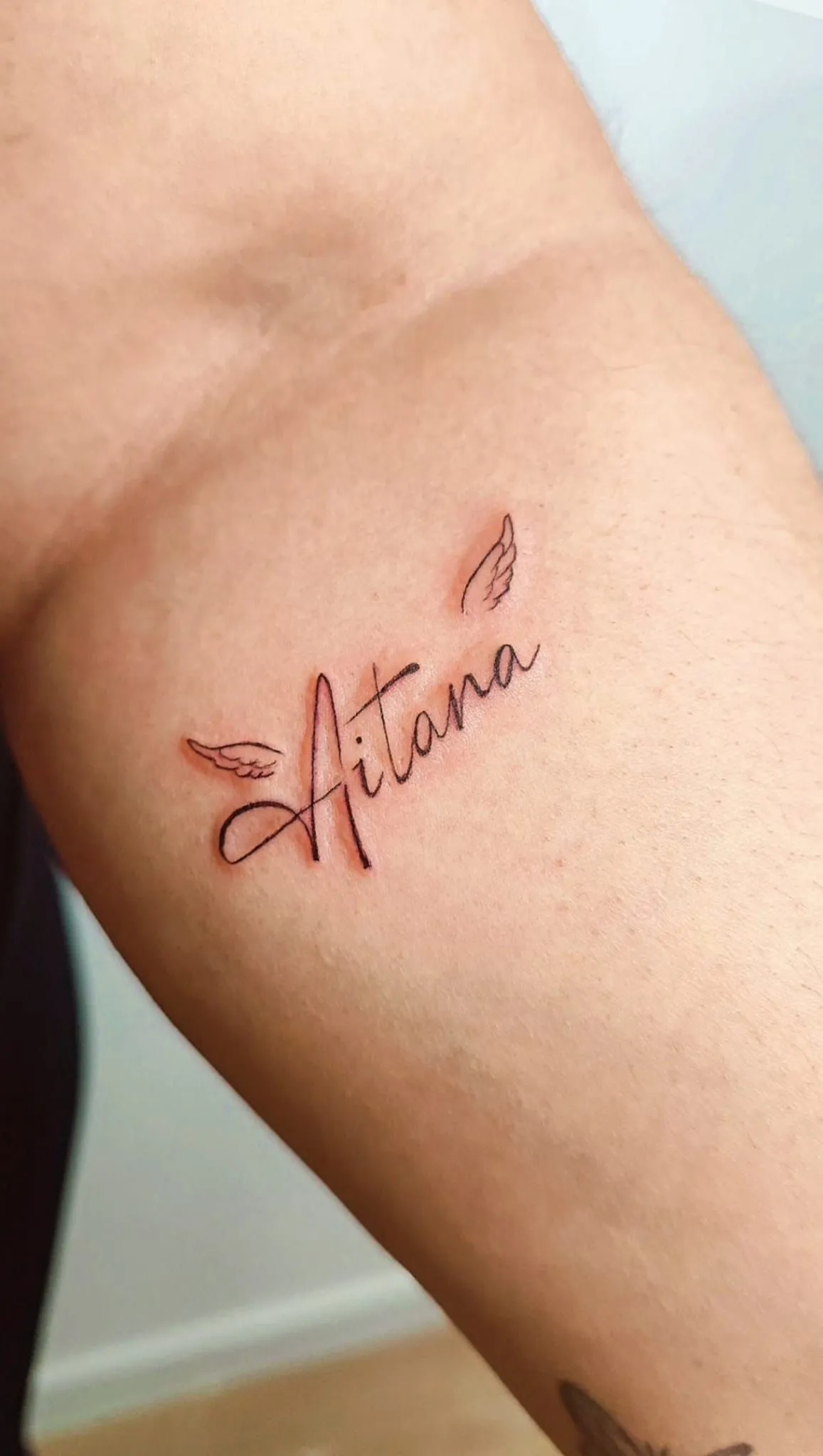 Antebrazo con un pequeño tatuaje de mariposa en letra cursiva.