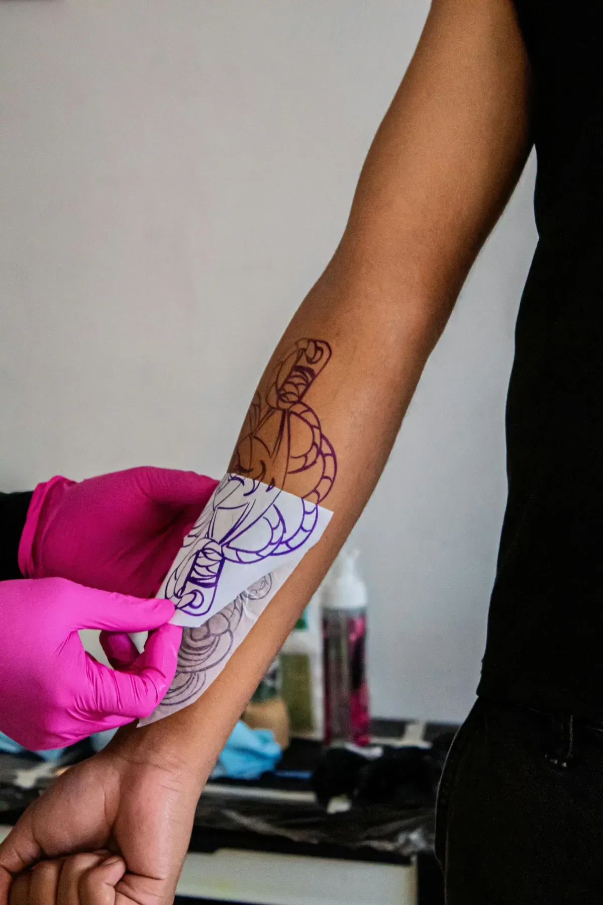 Antebrazo con una plantilla de tatuaje siendo trazada con tinta morada.
